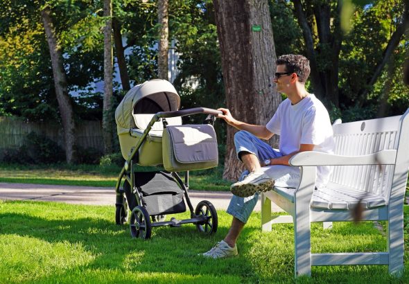 a man sitting on a bench next to a baby stroller